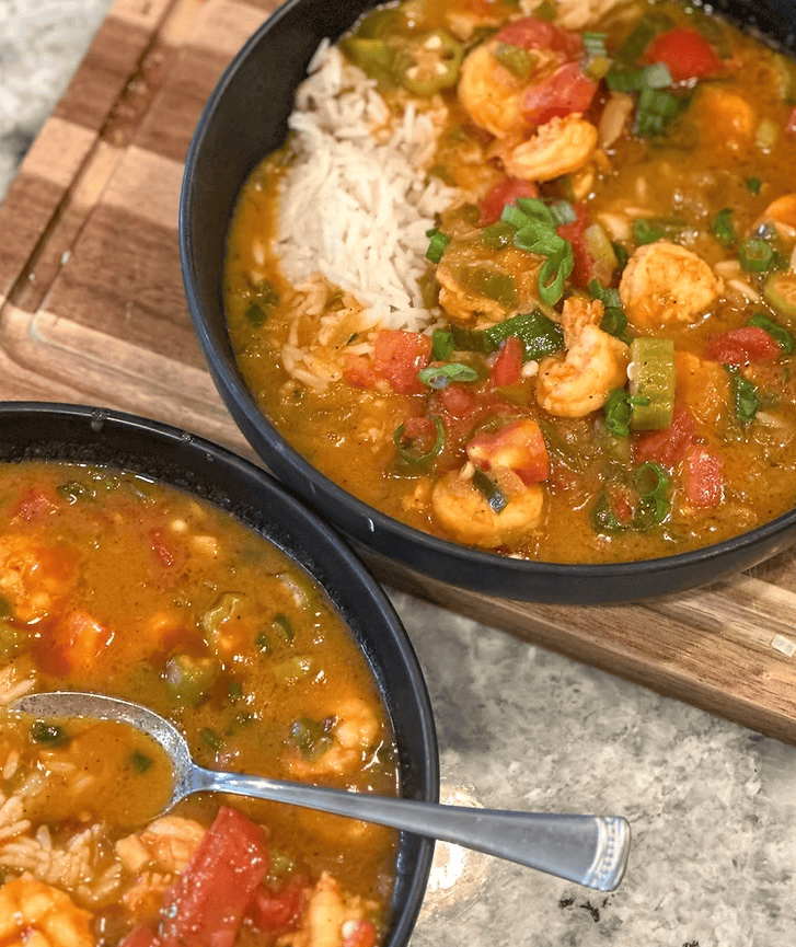 Shrimp étouffée served over white rice with okra, bell pepper, celery, onion, and green onions in a rich Cajun-style sauce.
