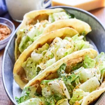 Chicken Caesar Smash Tacos made with seasoned ground chicken cooked on crispy pita bread and topped with fresh Caesar salad. This easy 20-minute dinner combines the flavors of chicken Caesar salad and smash tacos for a quick weeknight meal.