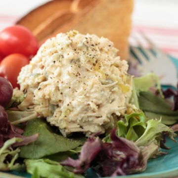 Creamy homemade chicken salad made with roasted seasoned chicken, bread and butter pickles, celery, onion, Duke's mayonnaise, and yellow mustard served in a white bowl.
