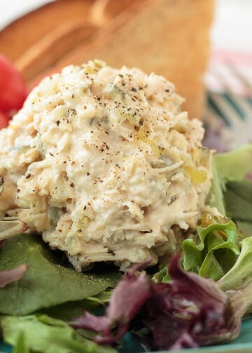 Creamy homemade chicken salad made with roasted seasoned chicken, bread and butter pickles, celery, onion, Duke's mayonnaise, and yellow mustard served in a white bowl.