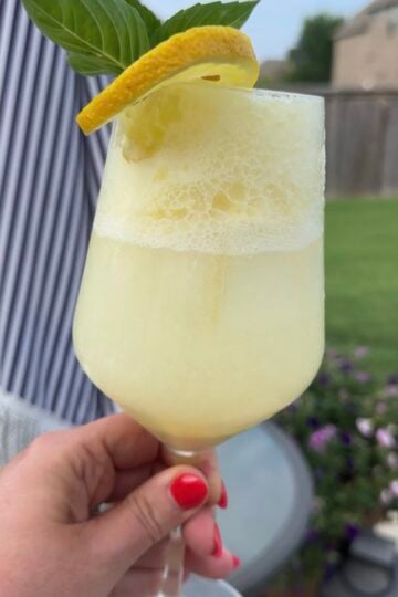 A refreshing Limoncello Spritz made with creamy limoncello, prosecco, and club soda, garnished with fresh mint and a lemon slice over ice.