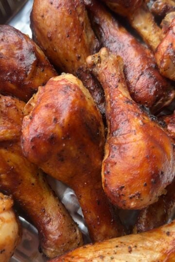 Smoked BBQ chicken drumsticks glazed with barbecue sauce on a white platter with fresh parsley.