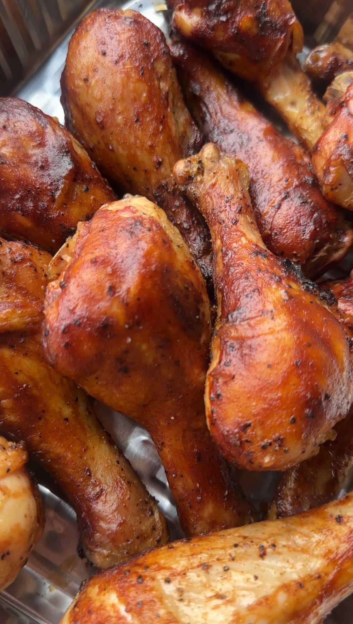 Smoked BBQ chicken drumsticks glazed with barbecue sauce on a white platter with fresh parsley.
