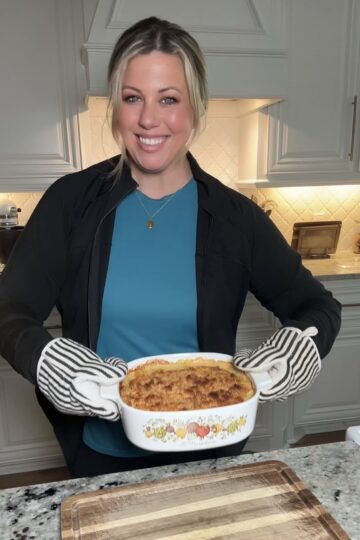 A serving of Neiman Marcus chicken casserole on a plate with green beans and a dinner roll