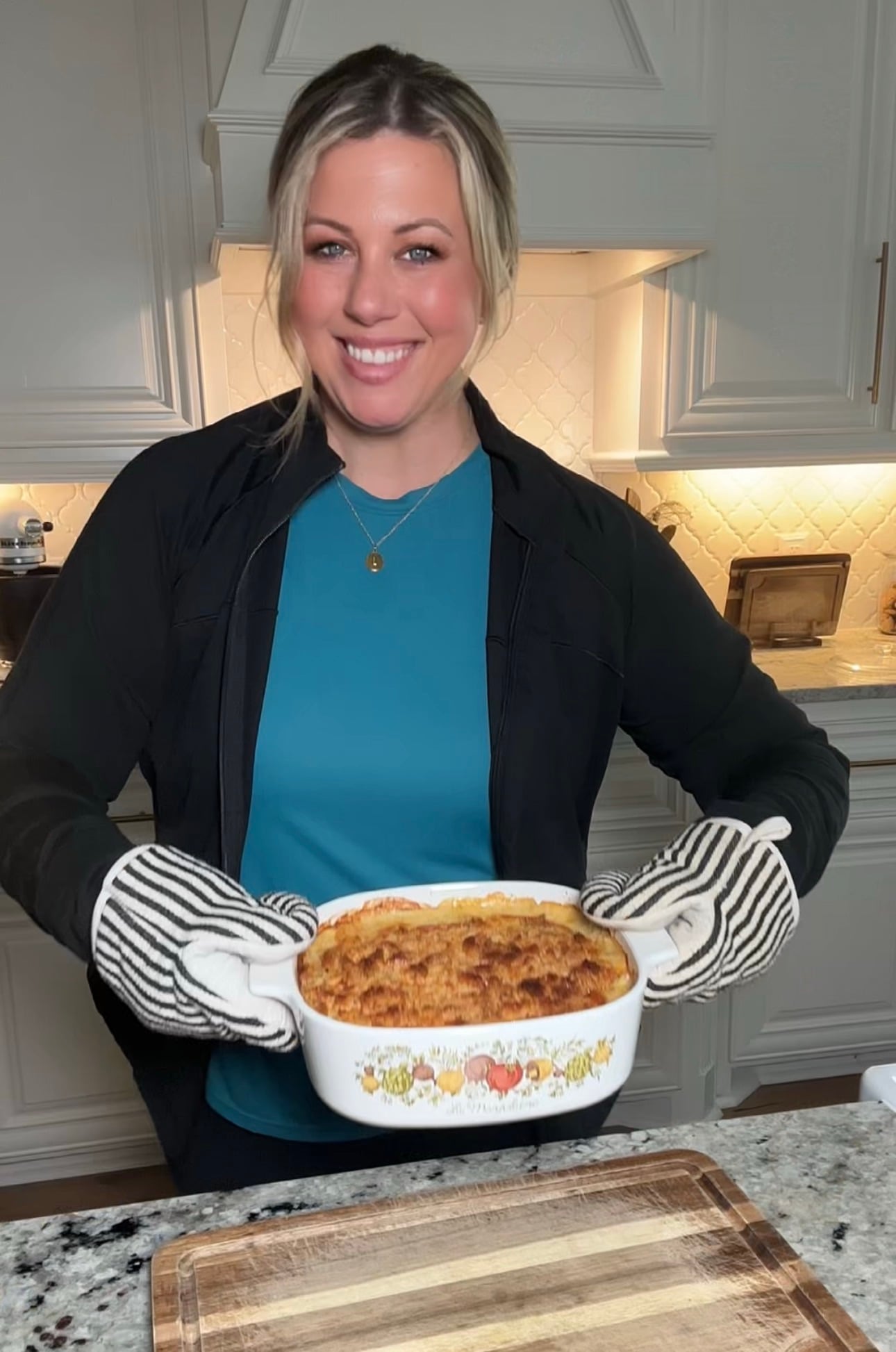 A serving of Neiman Marcus chicken casserole on a plate with green beans and a dinner roll