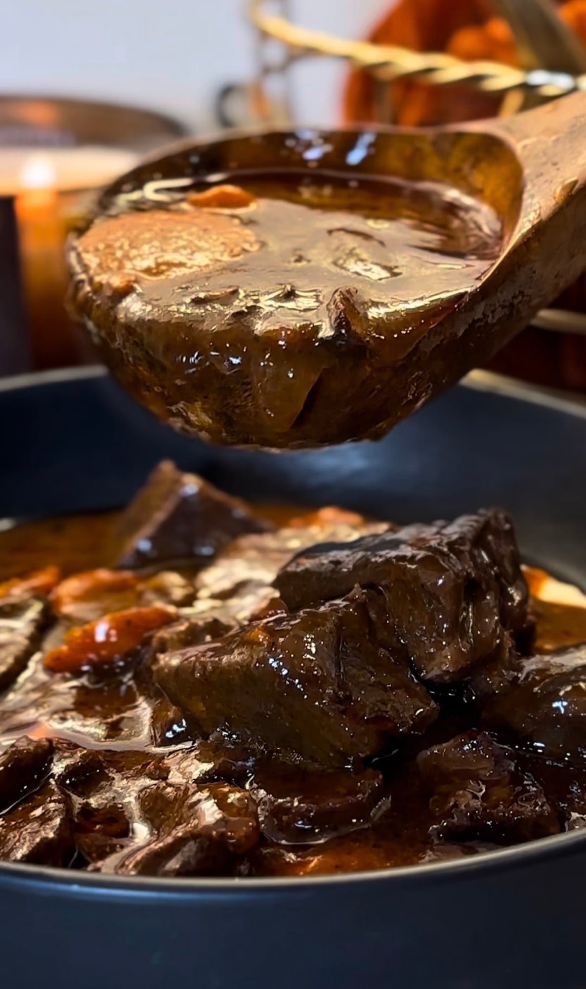 Beef bourguignon in a red Dutch oven with tender chunks of beef, mushrooms, pearl onions and carrots in a glossy red wine sauce