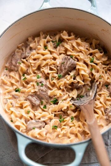 Quick beef stroganoff with chuck roast served over wide egg noodles in a skillet