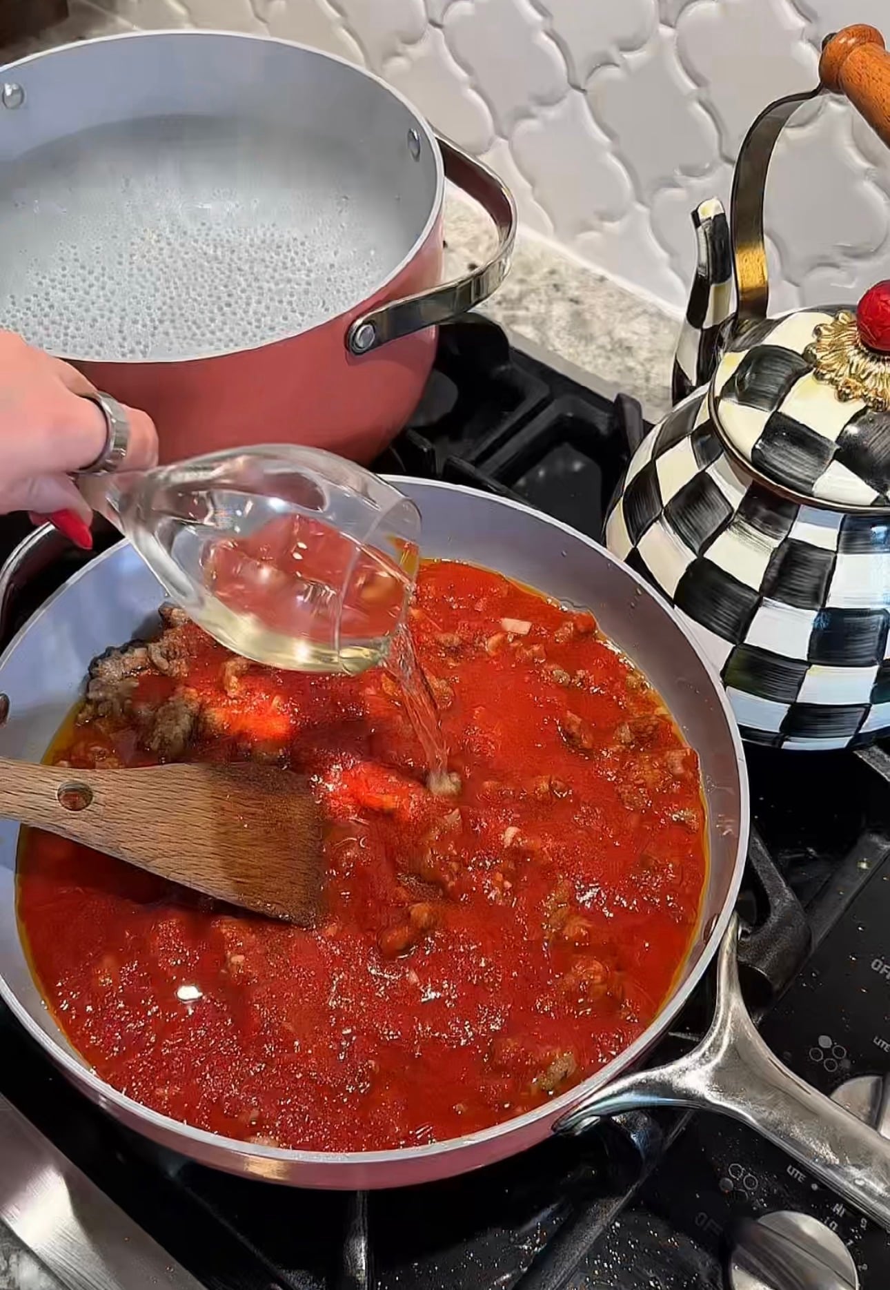 Dry white wine being poured into tomato sauce for orecchiette with Italian sausage.
