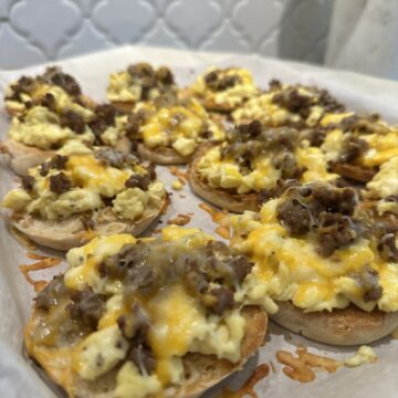 English muffin breakfast pizzas topped with eggs, sausage, and melted cheese