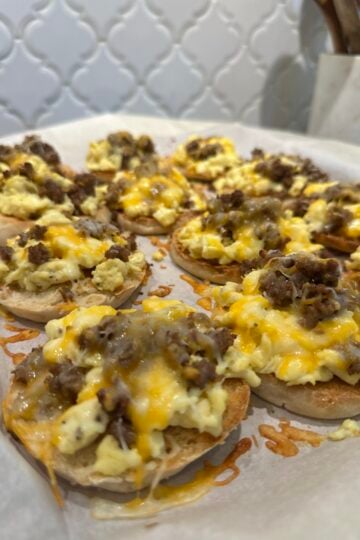 English muffin breakfast pizzas topped with eggs, sausage, and melted cheese