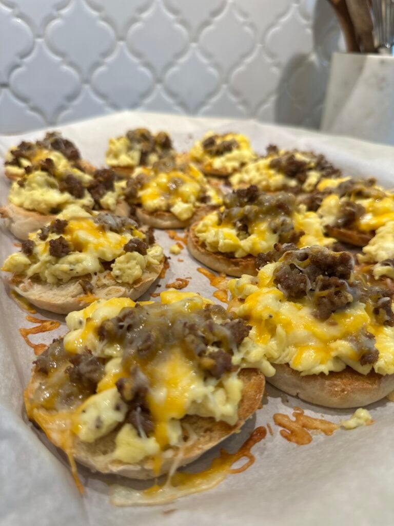 English muffin breakfast pizzas topped with eggs, sausage, and melted cheese