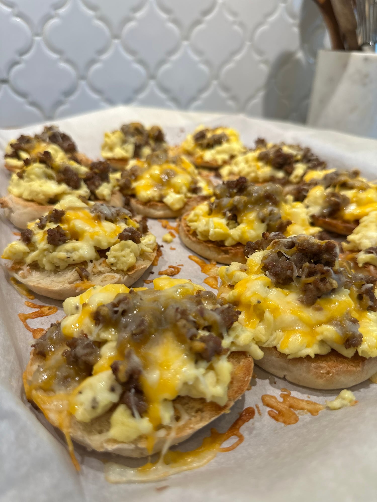 English muffin breakfast pizzas topped with eggs, sausage, and melted cheese