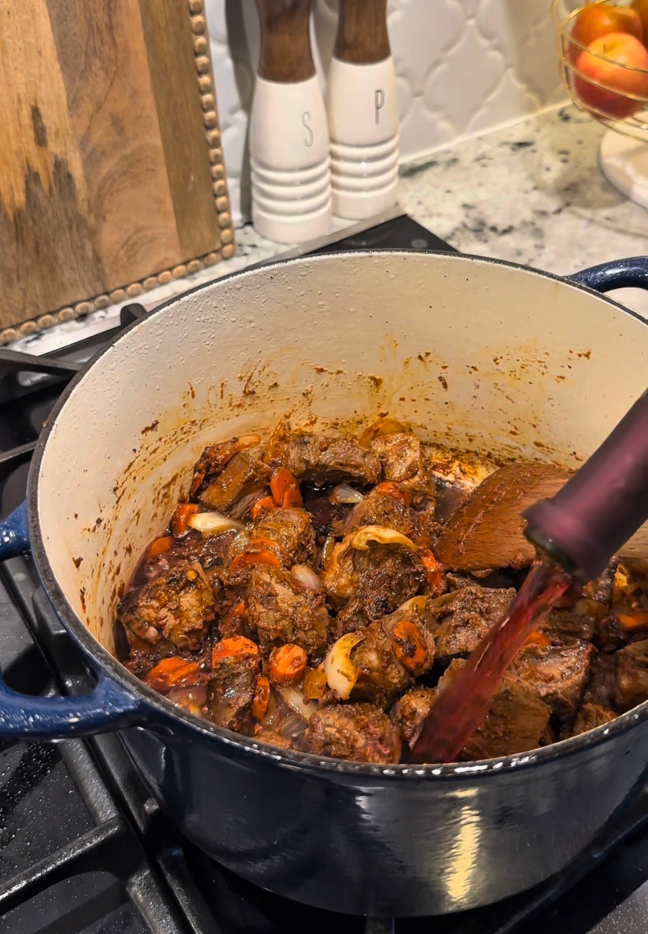Stovetop Beef Bourguignon simmering in a Dutch oven with tender chuck roast, carrots and mushrooms in red wine sauce