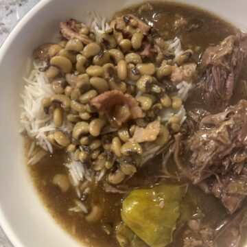 Crockpot Mississippi pot roast and gravy served over rice with purple hull peas.