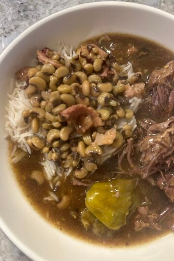 Crockpot Mississippi pot roast and gravy served over rice with purple hull peas.
