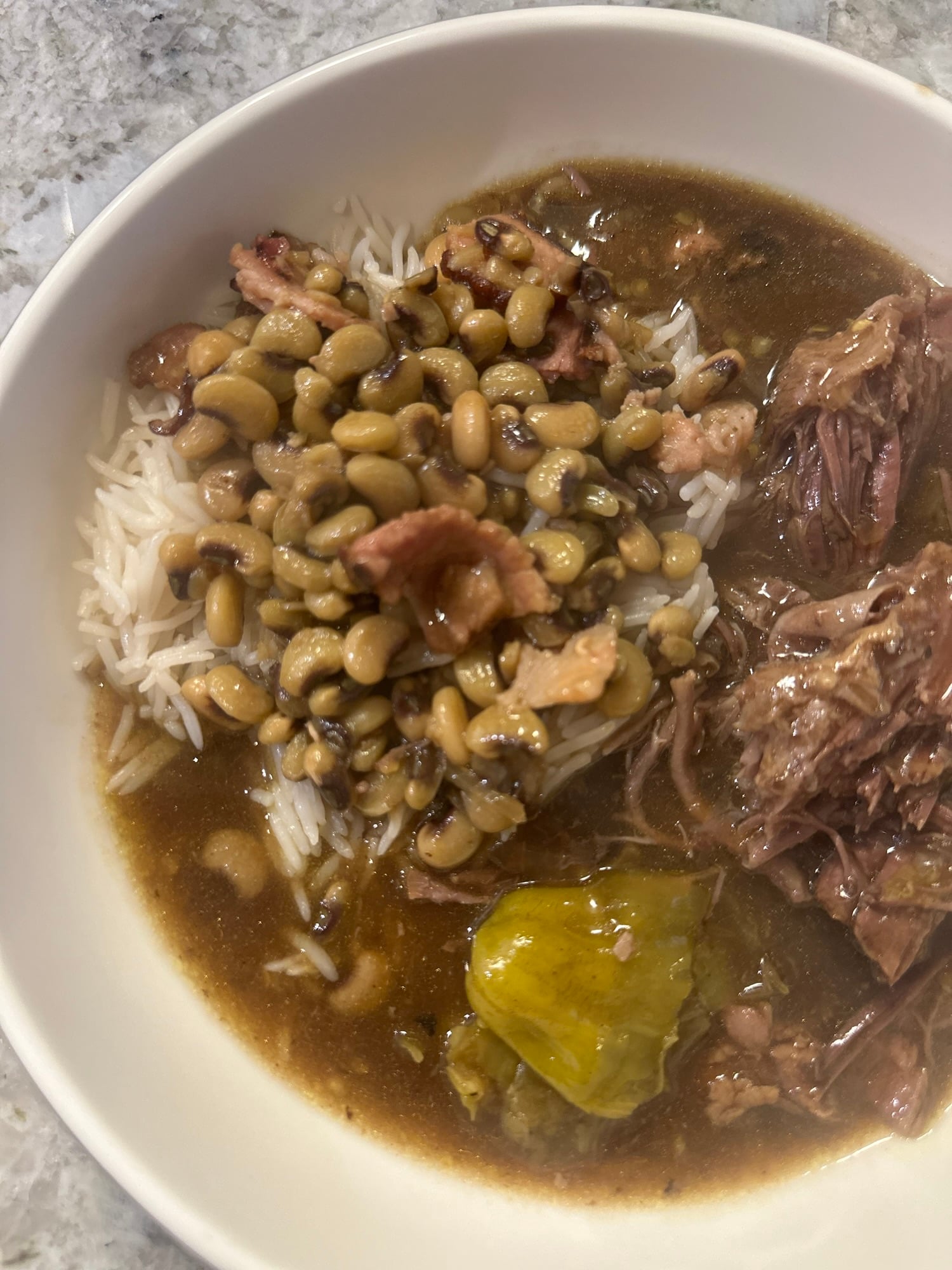 Crockpot Mississippi pot roast and gravy served over rice with purple hull peas.