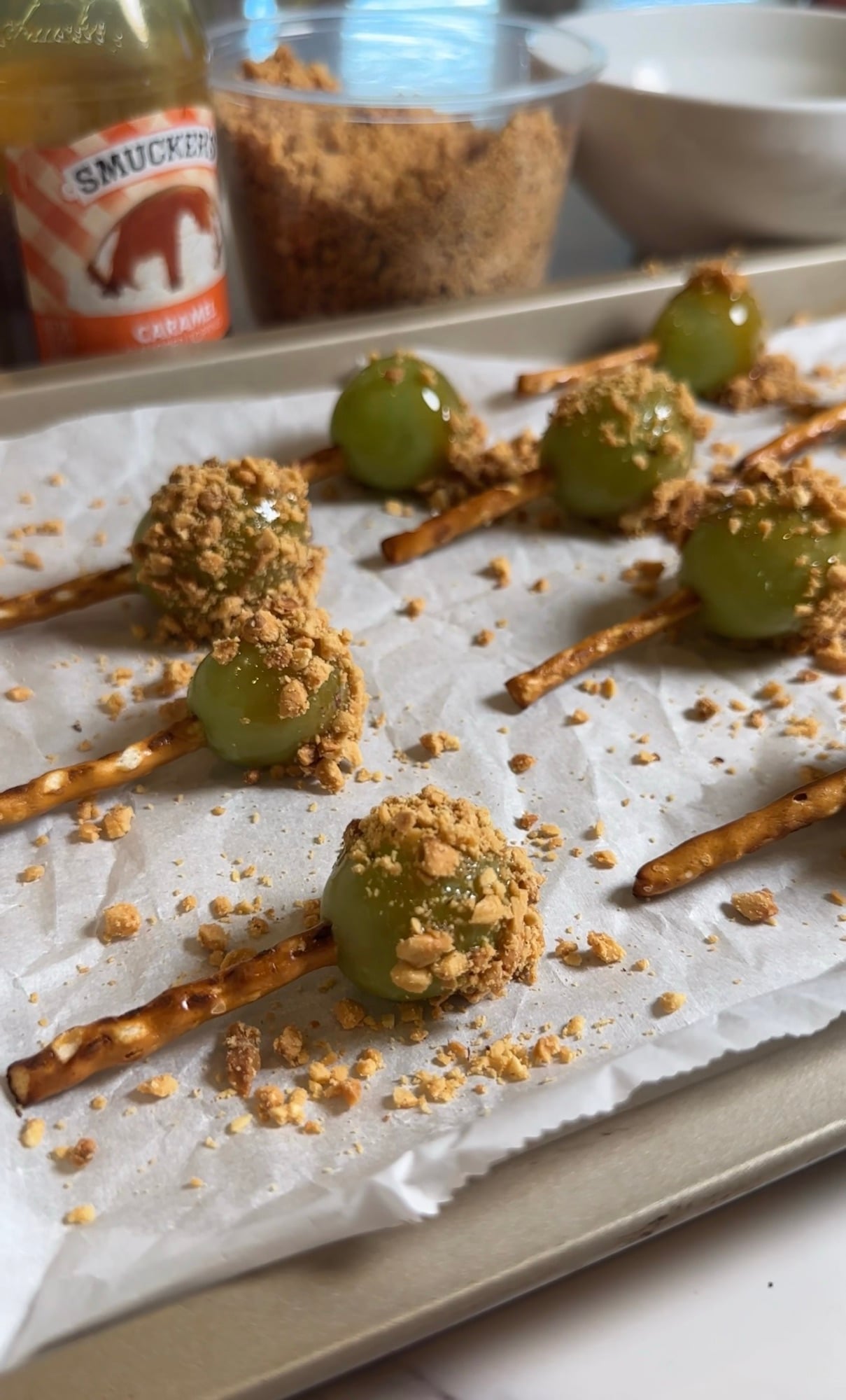 Green grapes dipped in caramel and chopped peanuts with pretzel sticks